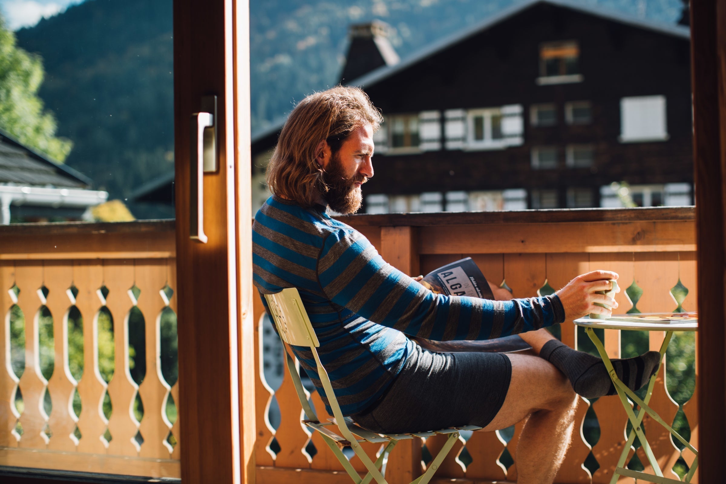 A man relaxing on a balcony in striped merino wool top and boxers