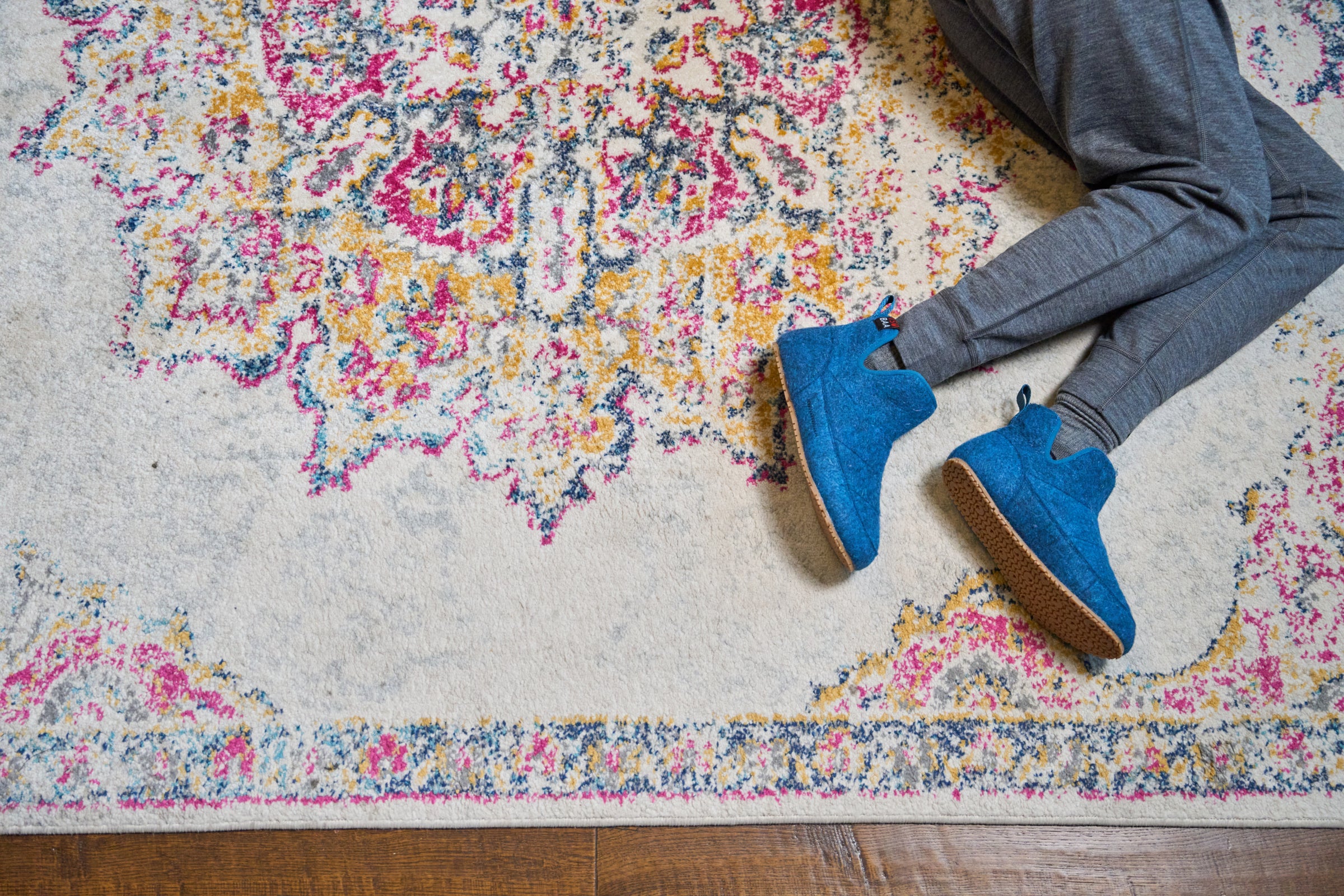Blaue Merino Blend Slipper Boots auf einem gemusterten Teppich, kombiniert mit grauem Loungewear