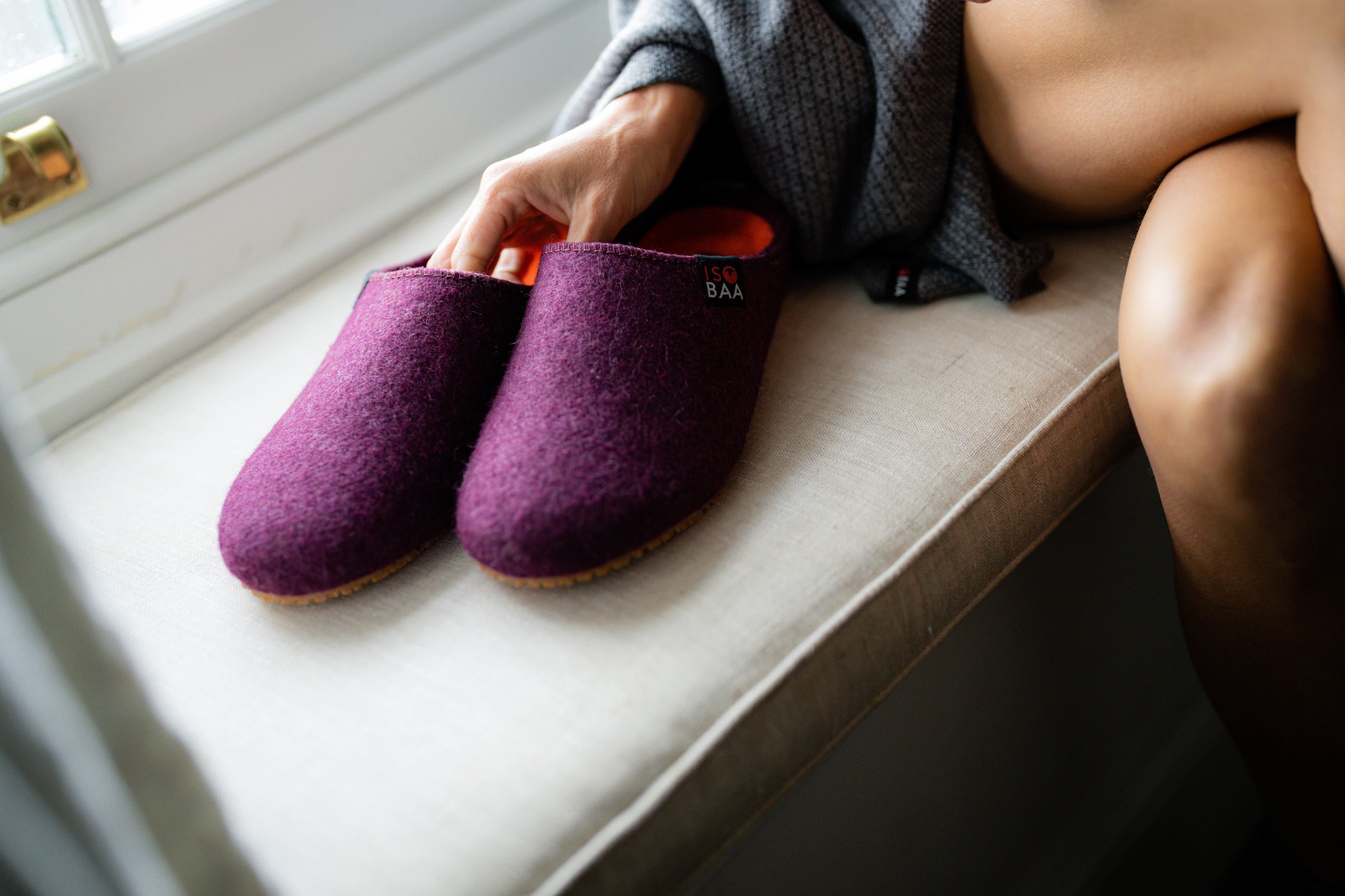 Lila Merino Blend Slippers mit orangefarbenem Futter auf einer Fensterbank