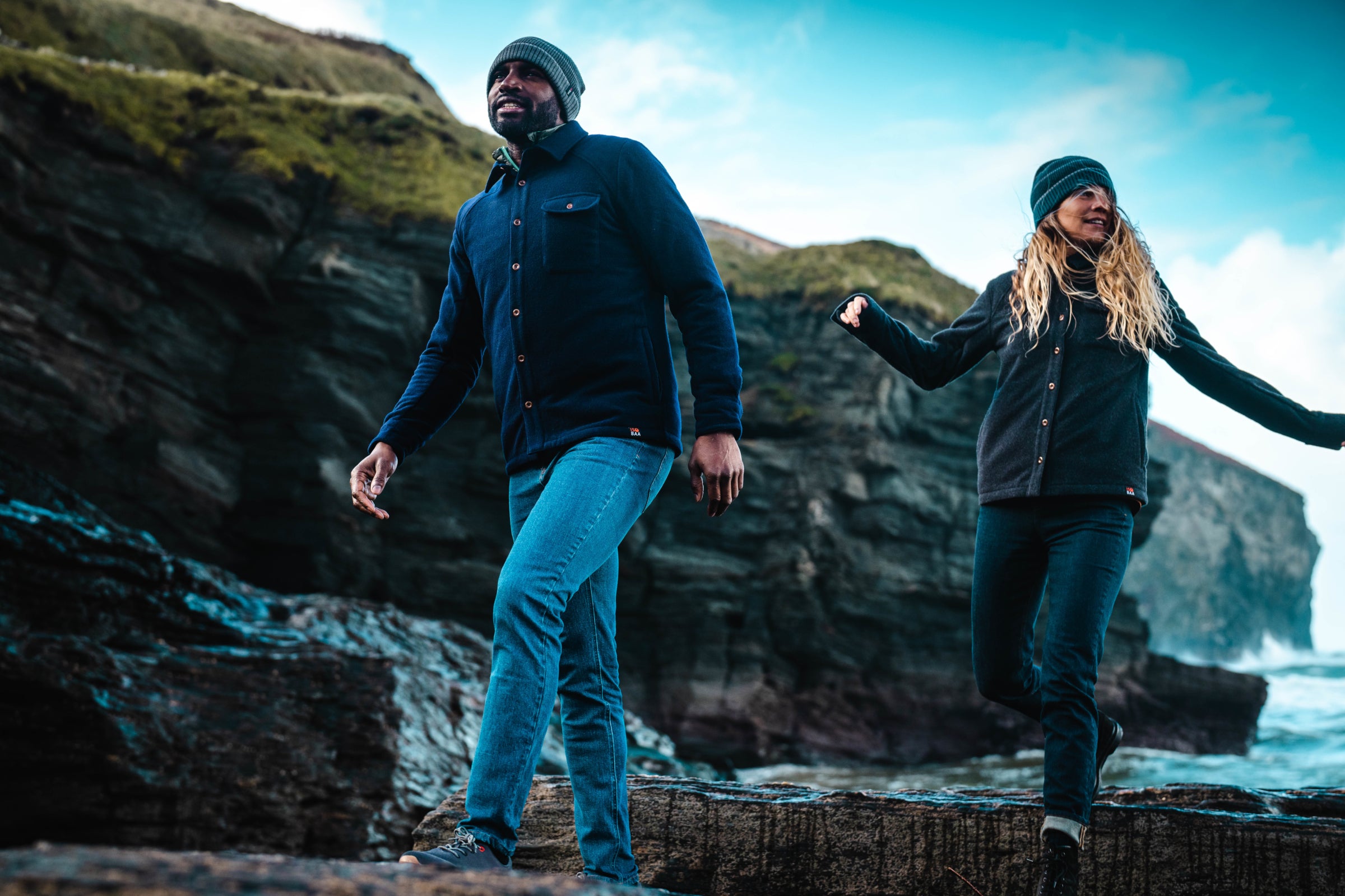 Two people walking along a rocky coastal path